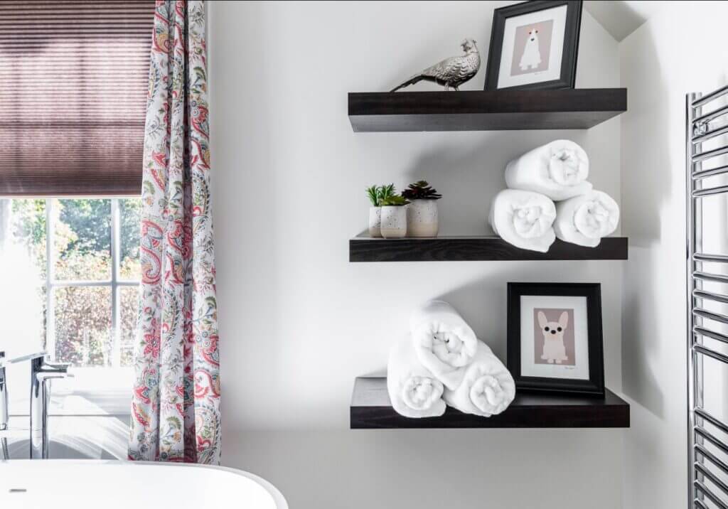 dark wood floating shelves in a white bathroom